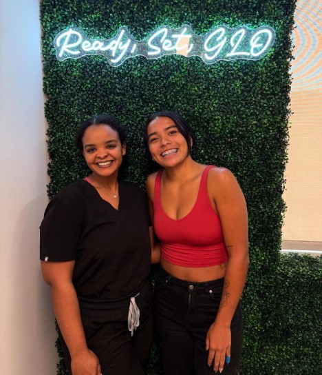 Behl Orthodontics team member and smiling teen at the Ready, Set, Glo wall